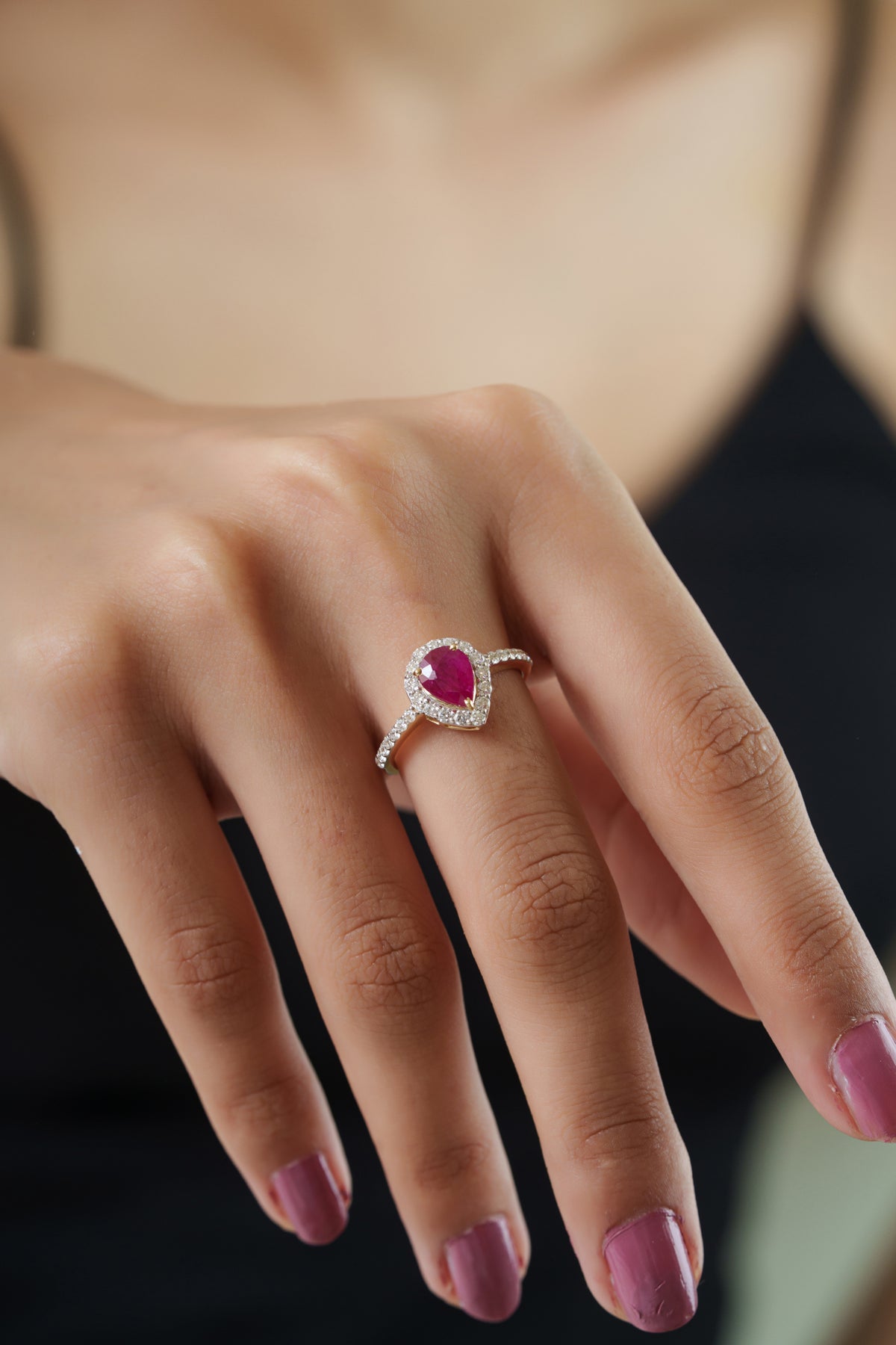 gold pear-shaped ruby halo ring featuring a natural ruby center, round diamond halo, and pavé diamond band in a timeless engagement design.