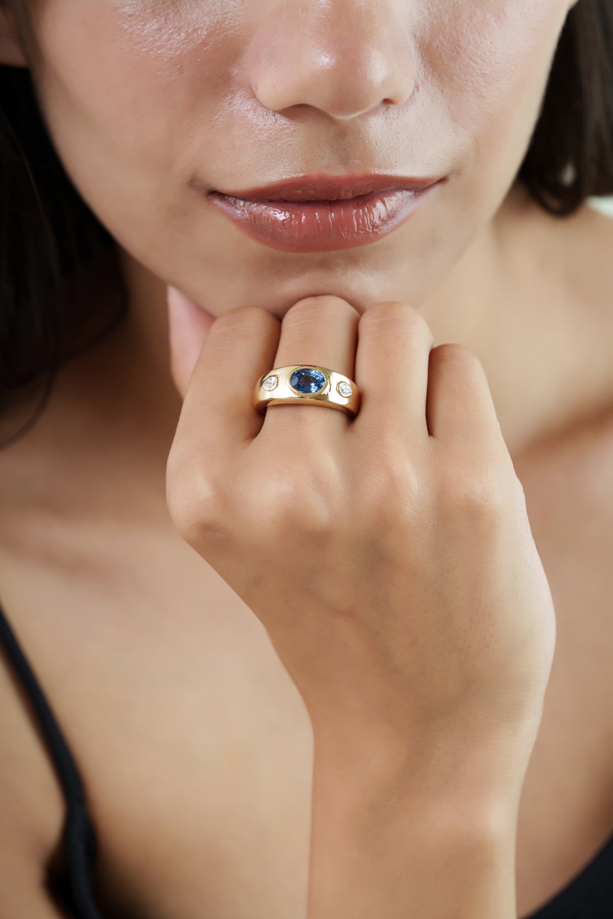 gold signet ring featuring a natural oval blue sapphire with two pear-shaped diamond accents in a polished wide-band design.