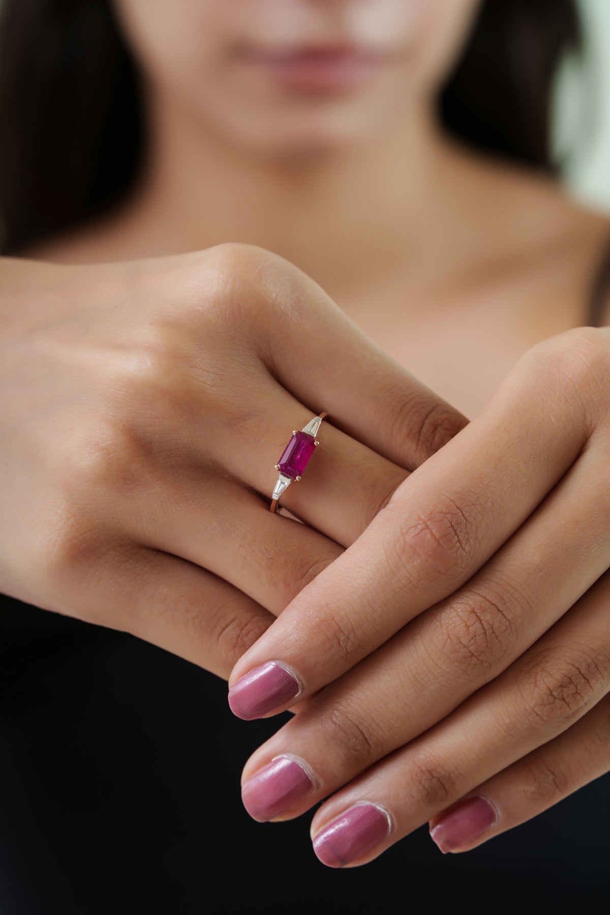 Emerald cut ruby ring with tapered baguette diamond side stones on a minimalist polished gold band.