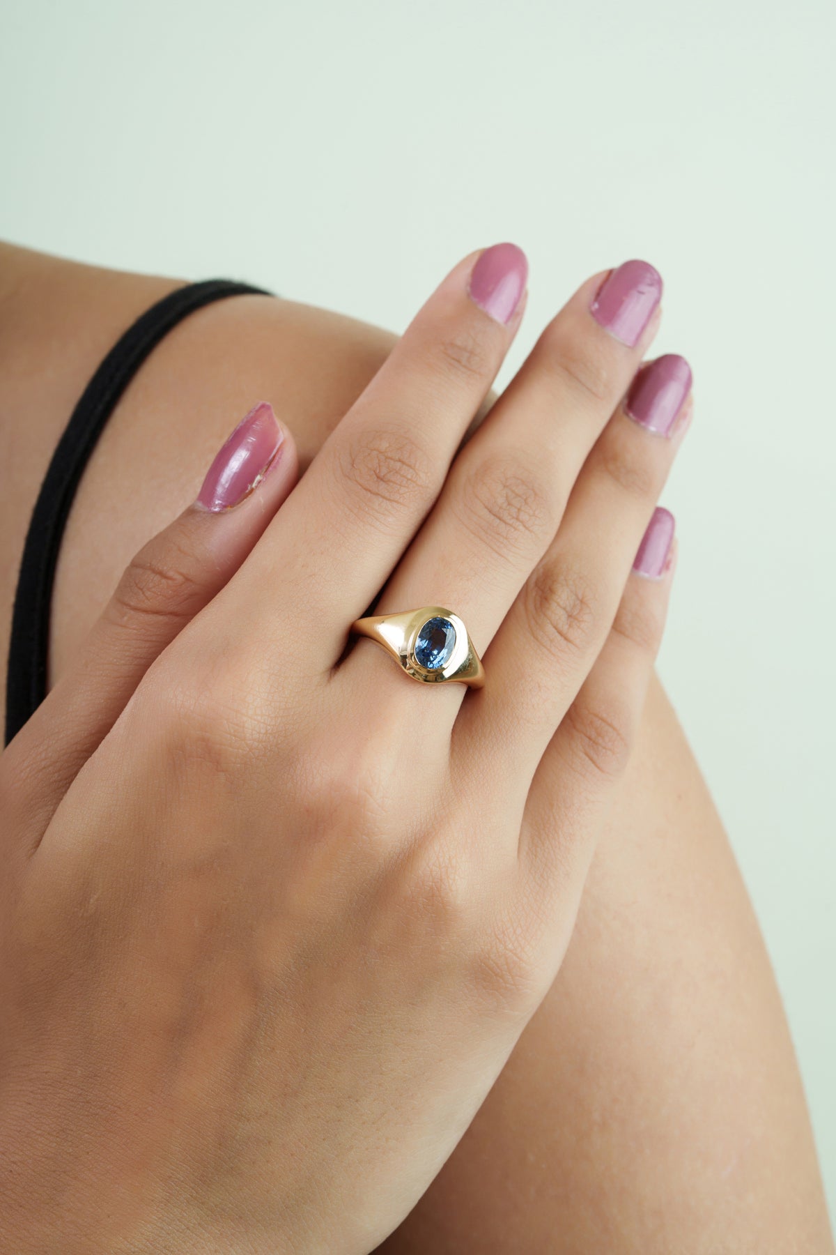 Solid 14K gold signet ring featuring a natural oval blue sapphire in a smooth bezel setting with a polished minimalist finish.